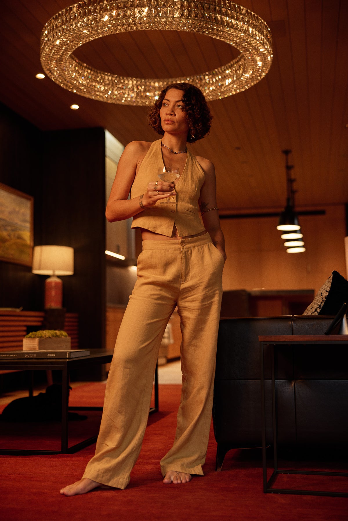 A woman in camel linen in a warm hotel lobby at night